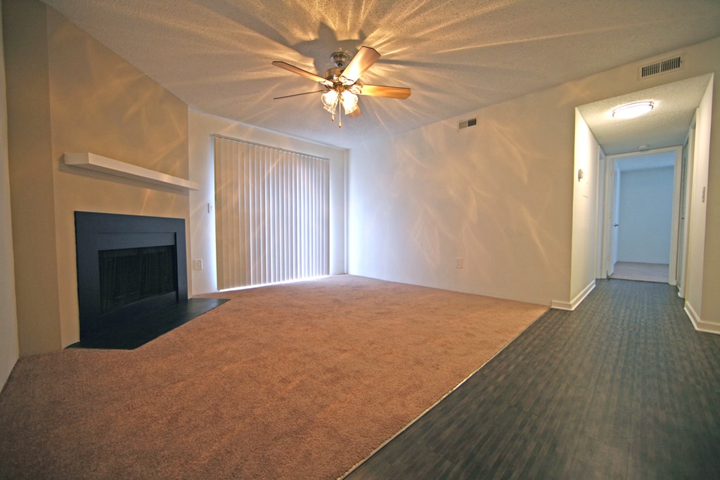 an empty living room with a fireplace and a ceiling fan
