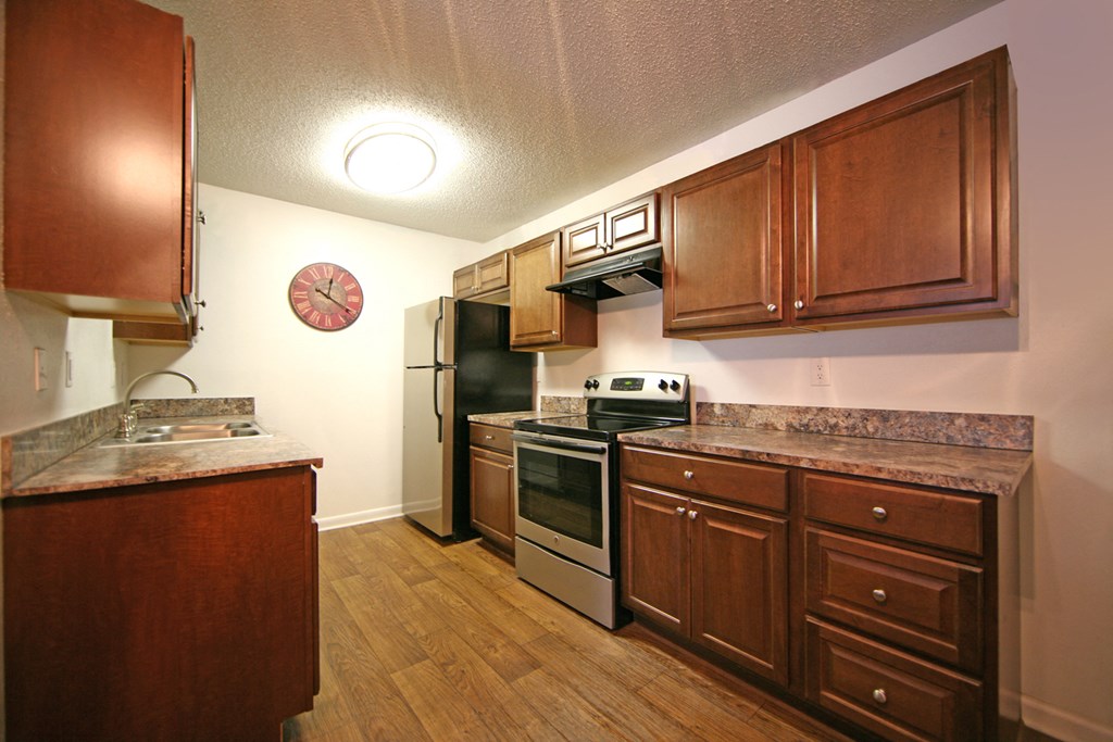 a kitchen with wooden cabinets and stainless steel appliances and a clock on the wall