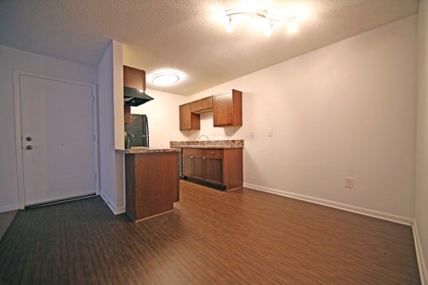 an empty living room and kitchen with wood flooring and