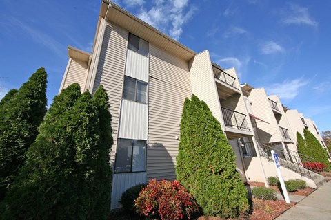 an apartment building with trees and shrubs in front of it