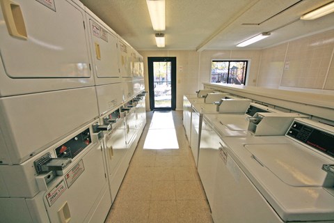 a laundry room with rows of washers and dryers