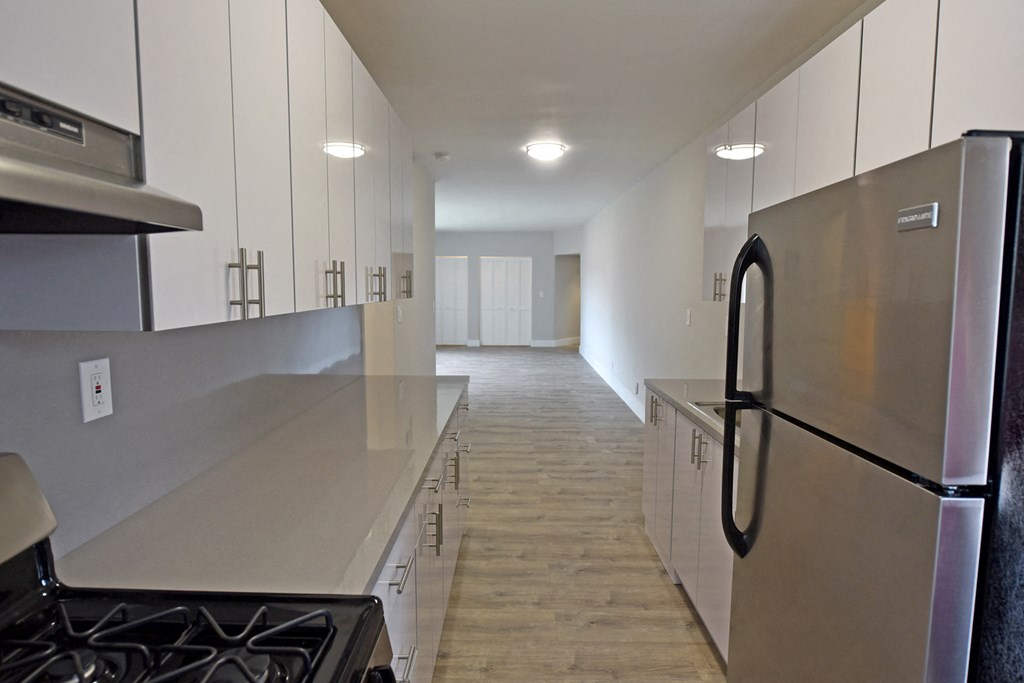 an empty kitchen with stainless steel appliances and white cabinets