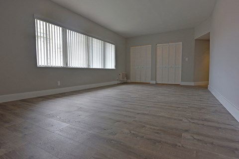 an empty living room with wood floors and windows