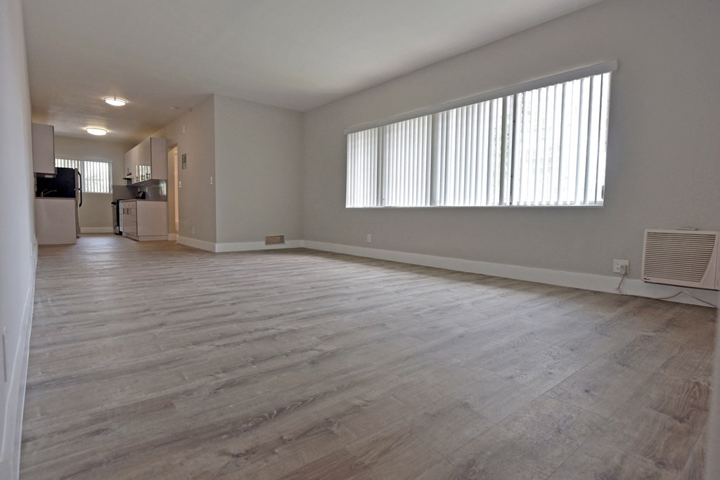 an empty living room with wood floors and a large window