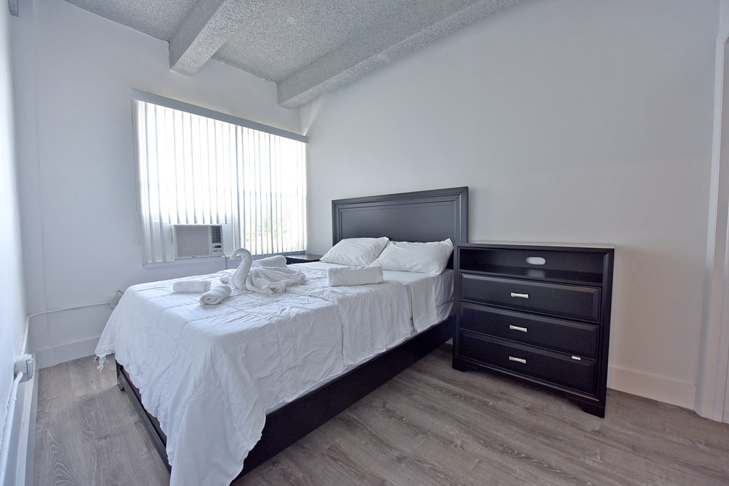 a bedroom with a bed and a dresser and a window