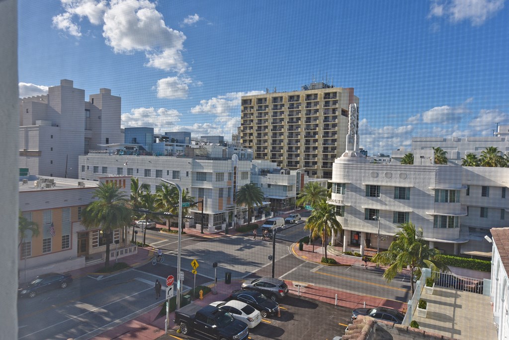 a view of a city street from a window with palm trees