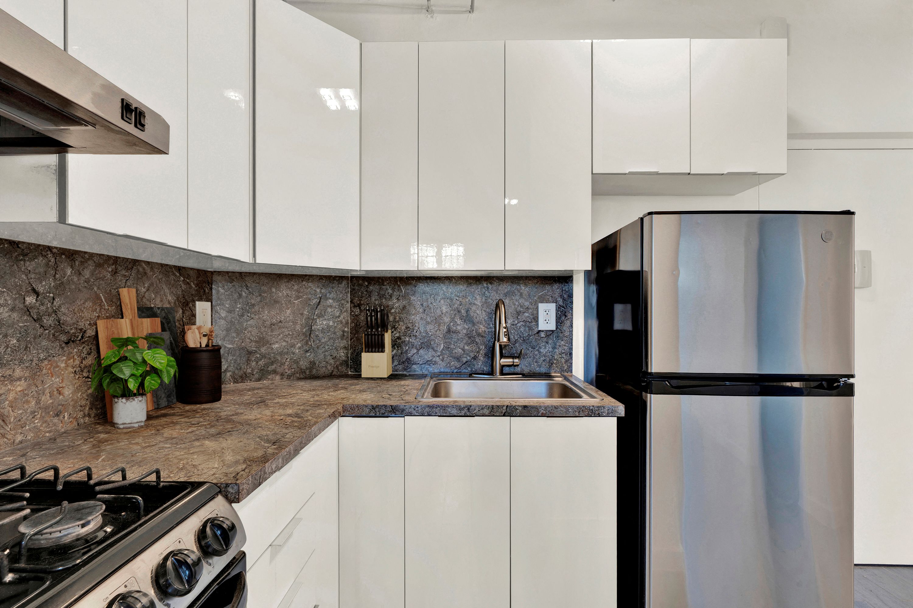 A modern kitchen with a stainless steel refrigerator and a granite countertop.