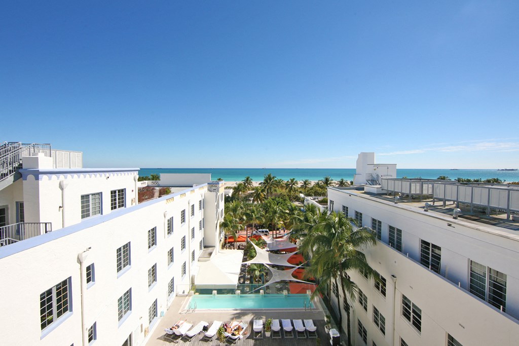 a view of the pool and the ocean from the roof of a hotel