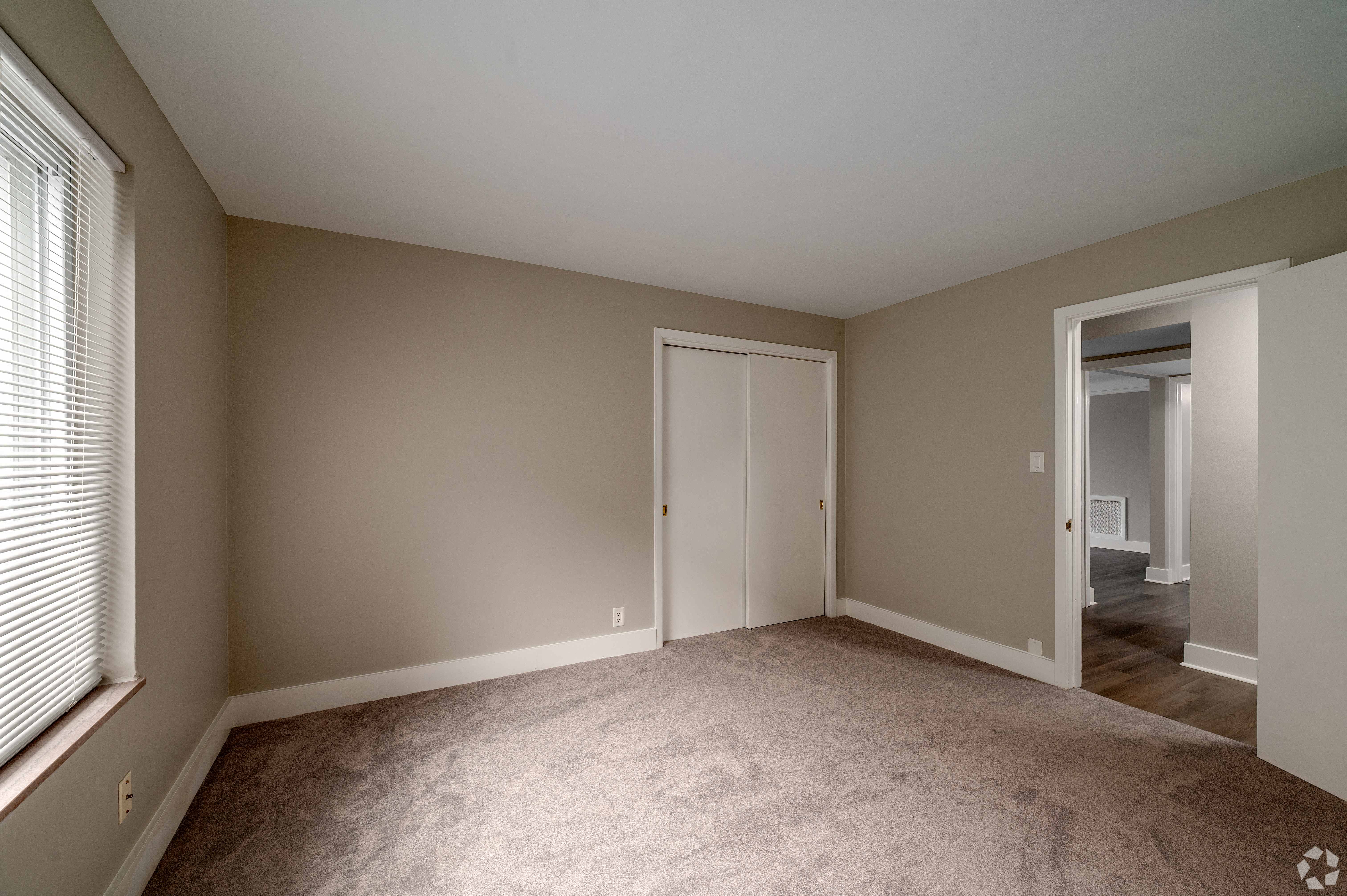 a bedroom with a carpeted floor and a door to a hallway