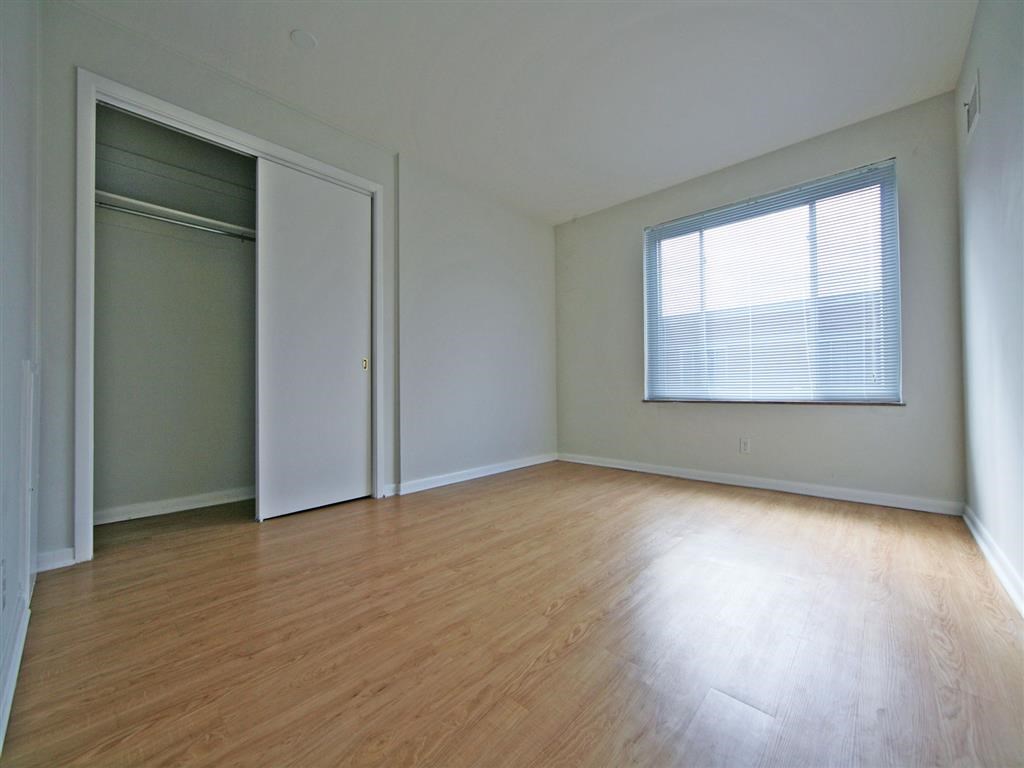 an empty living room with wood floors and a closet