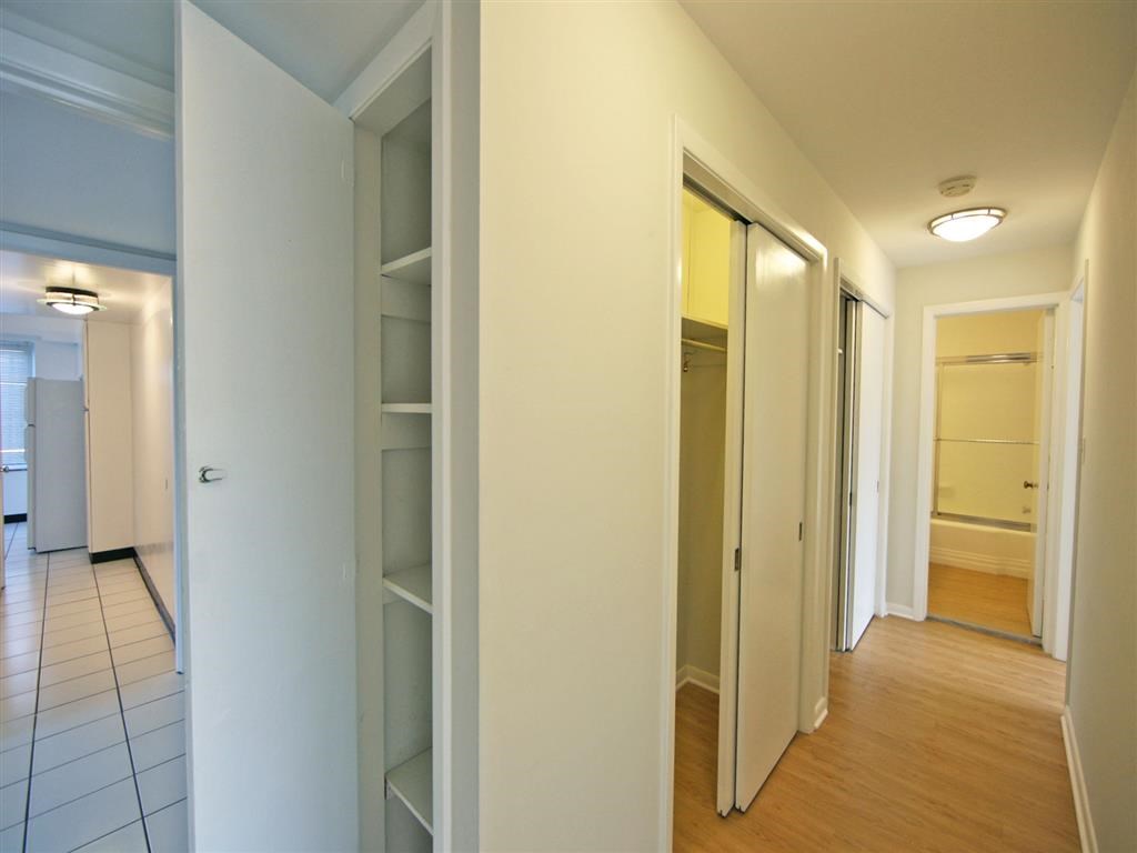 a walk in closet with mirrored doors and a wood floor