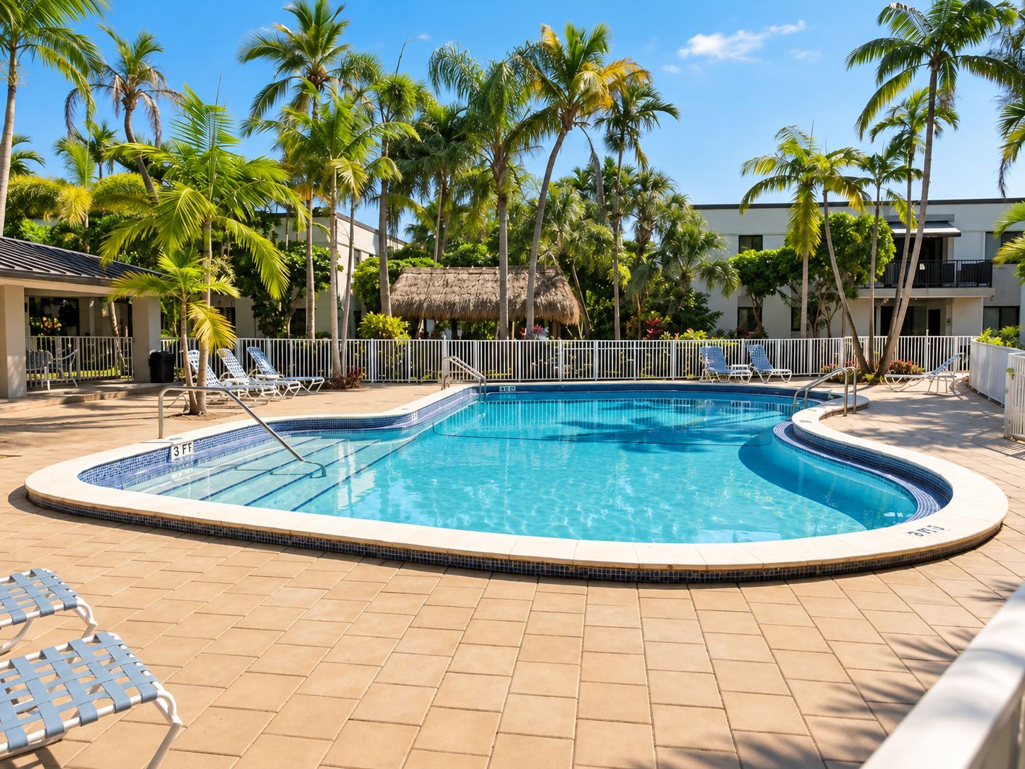 A swimming pool surrounded by palm trees and lounge chairs.
