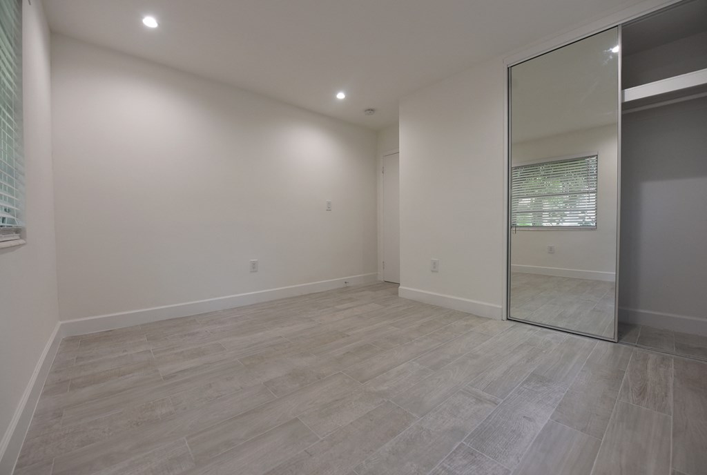 an empty living room with a sliding glass door to a bathroom