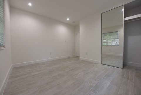 an empty living room with a sliding glass door to a bathroom
