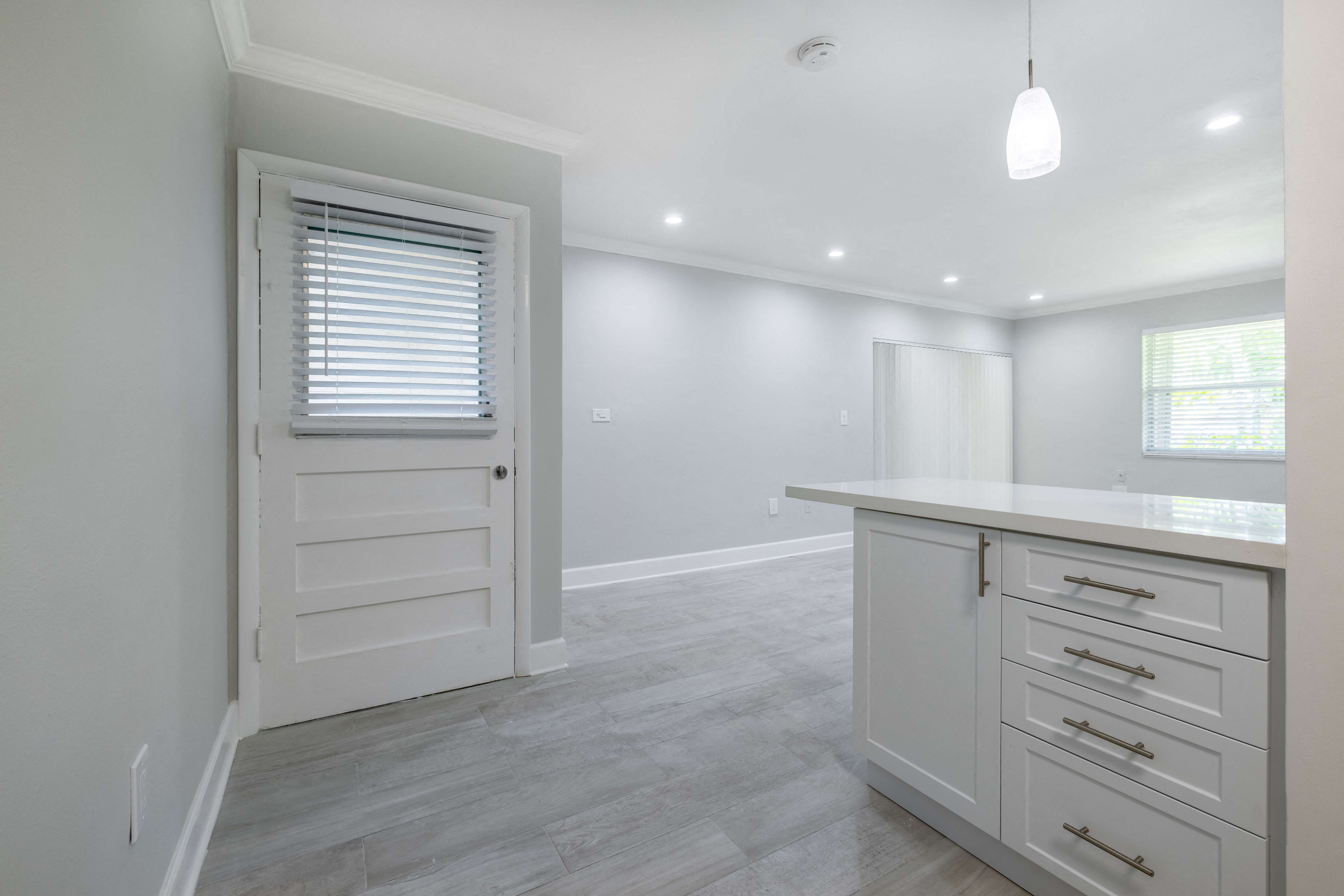 a white kitchen with white cabinets and a white door