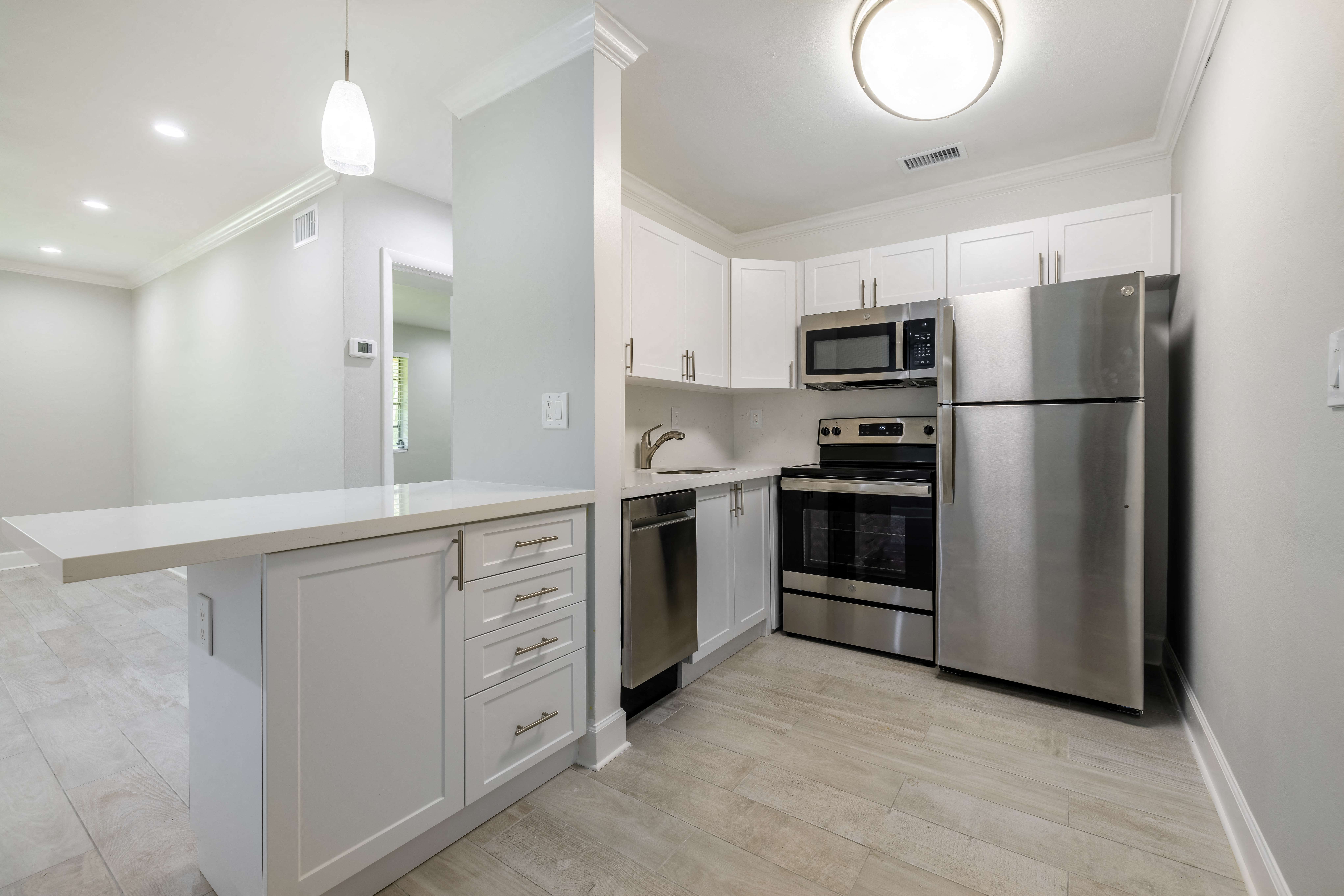 a white kitchen with stainless steel appliances and white cabinets