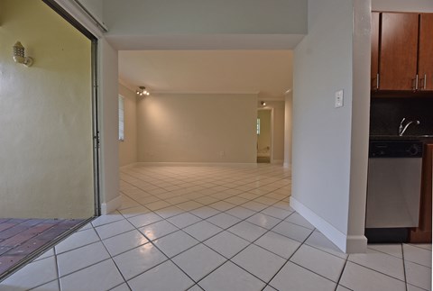 an empty living room with a tiled floor and a sliding glass door