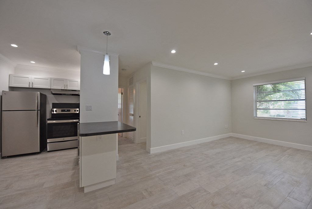 an empty kitchen and living room with a refrigerator and a sink