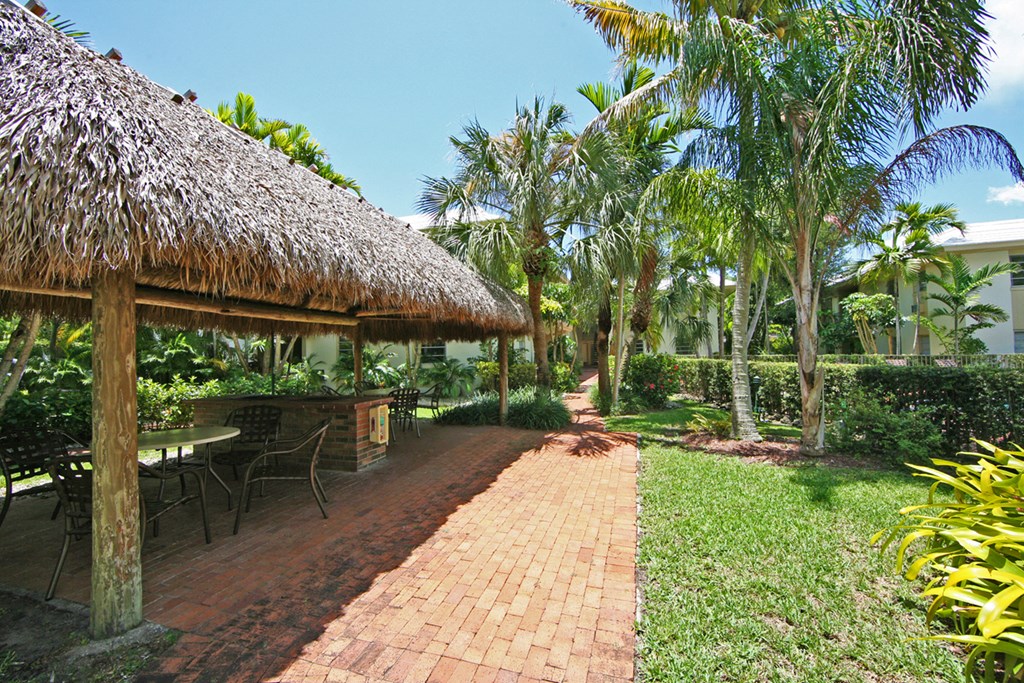 a patio with a hut and a table and chairs in a garden