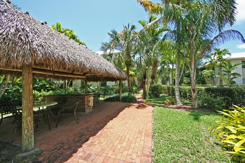 a patio with a hut and a table and chairs in a garden