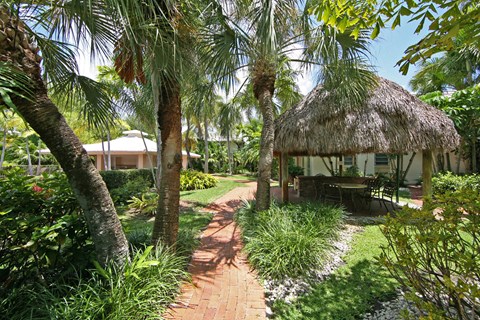 a path leading to a thatched hut in a garden