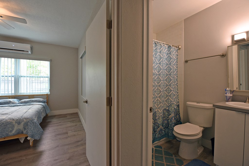 a bedroom with a bed and a bathroom with a toilet and a shower