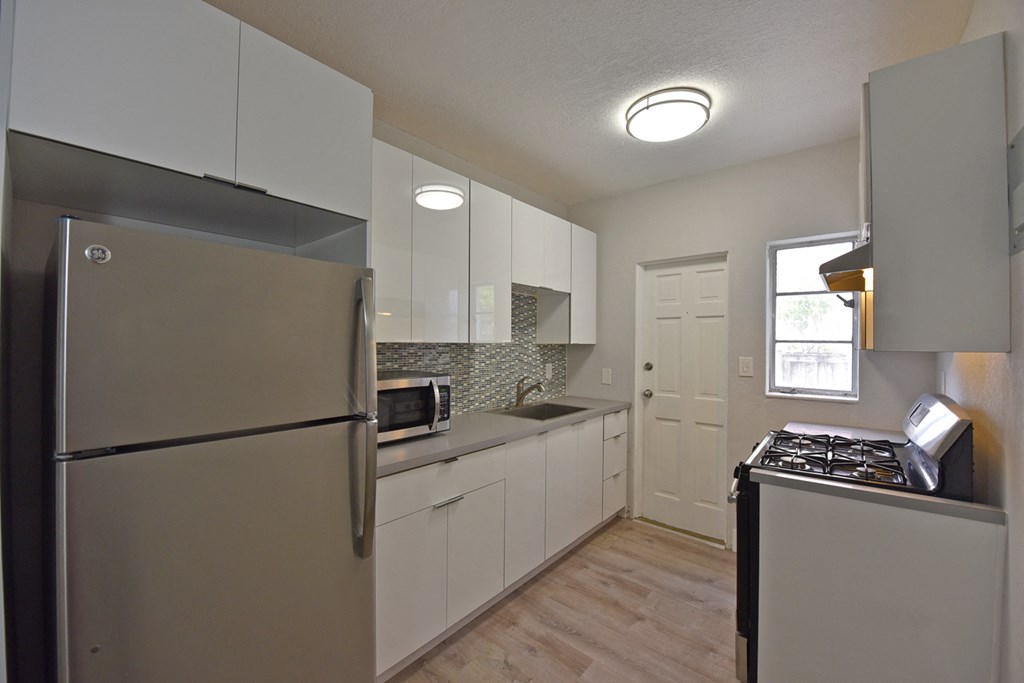 a kitchen with white cabinets and stainless steel appliances and a refrigerator