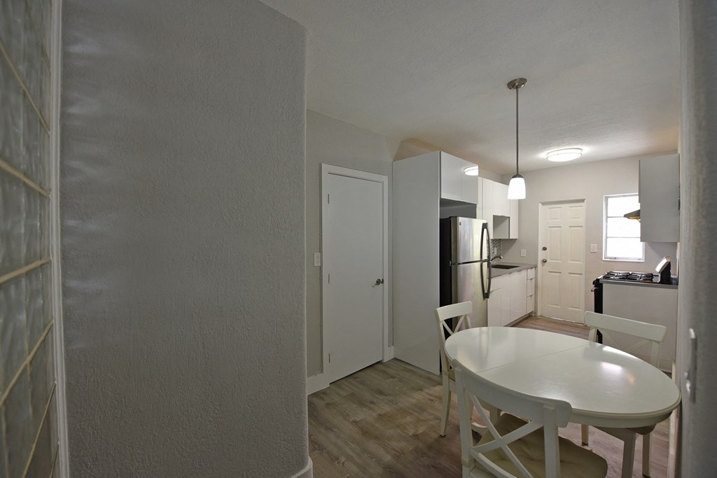 an empty kitchen and dining room with a white table and chairs