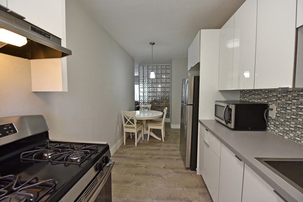 a kitchen and dining room with white cabinets and stainless steel appliances