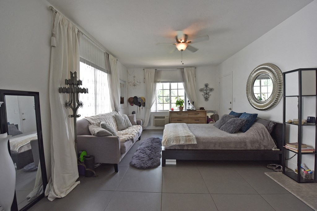 a bedroom with a couch and a bed and a ceiling fan