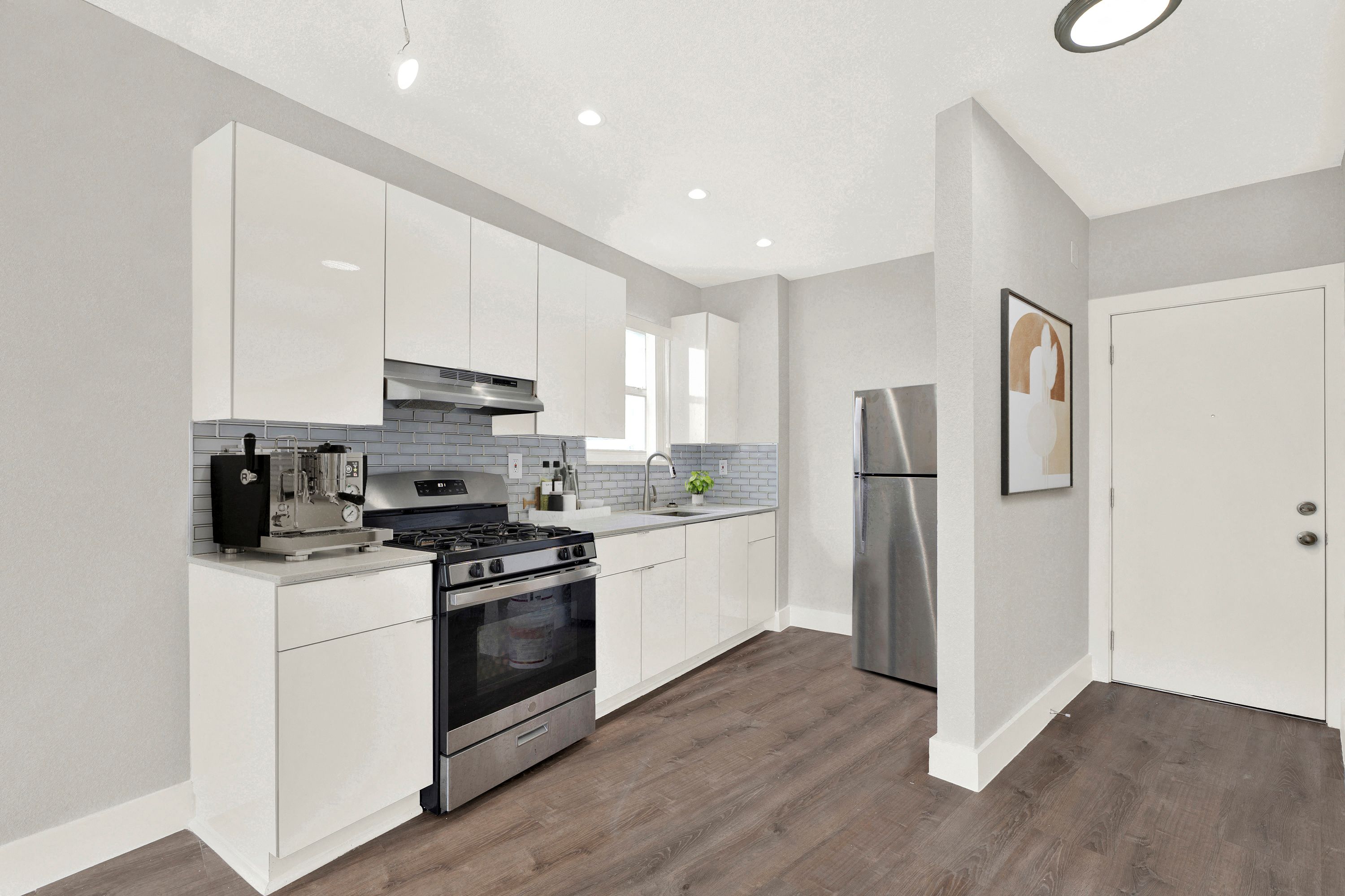 A modern kitchen with white cabinets and stainless steel appliances.
