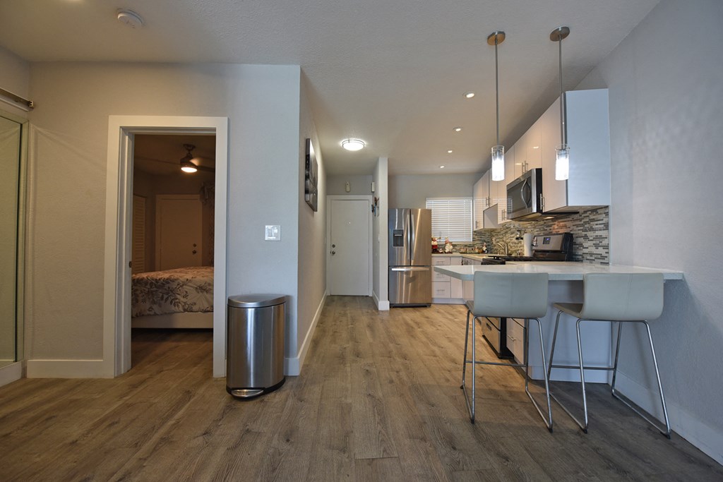a kitchen and living room with a bar and stools in a house