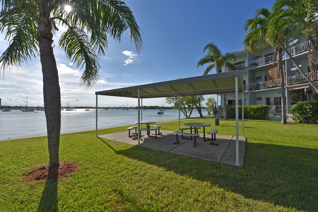 a park with benches and a canopy next to a body of water
