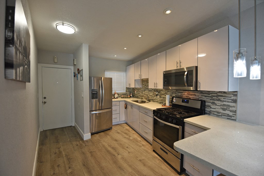 an open kitchen with stainless steel appliances and white cabinets