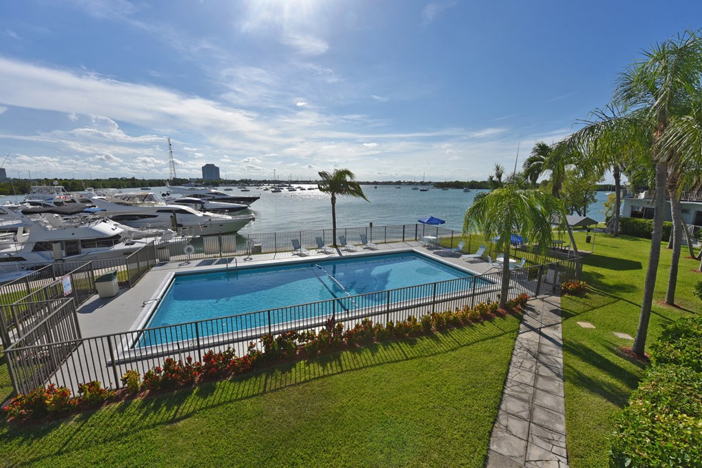 a large swimming pool in front of a marina with boats