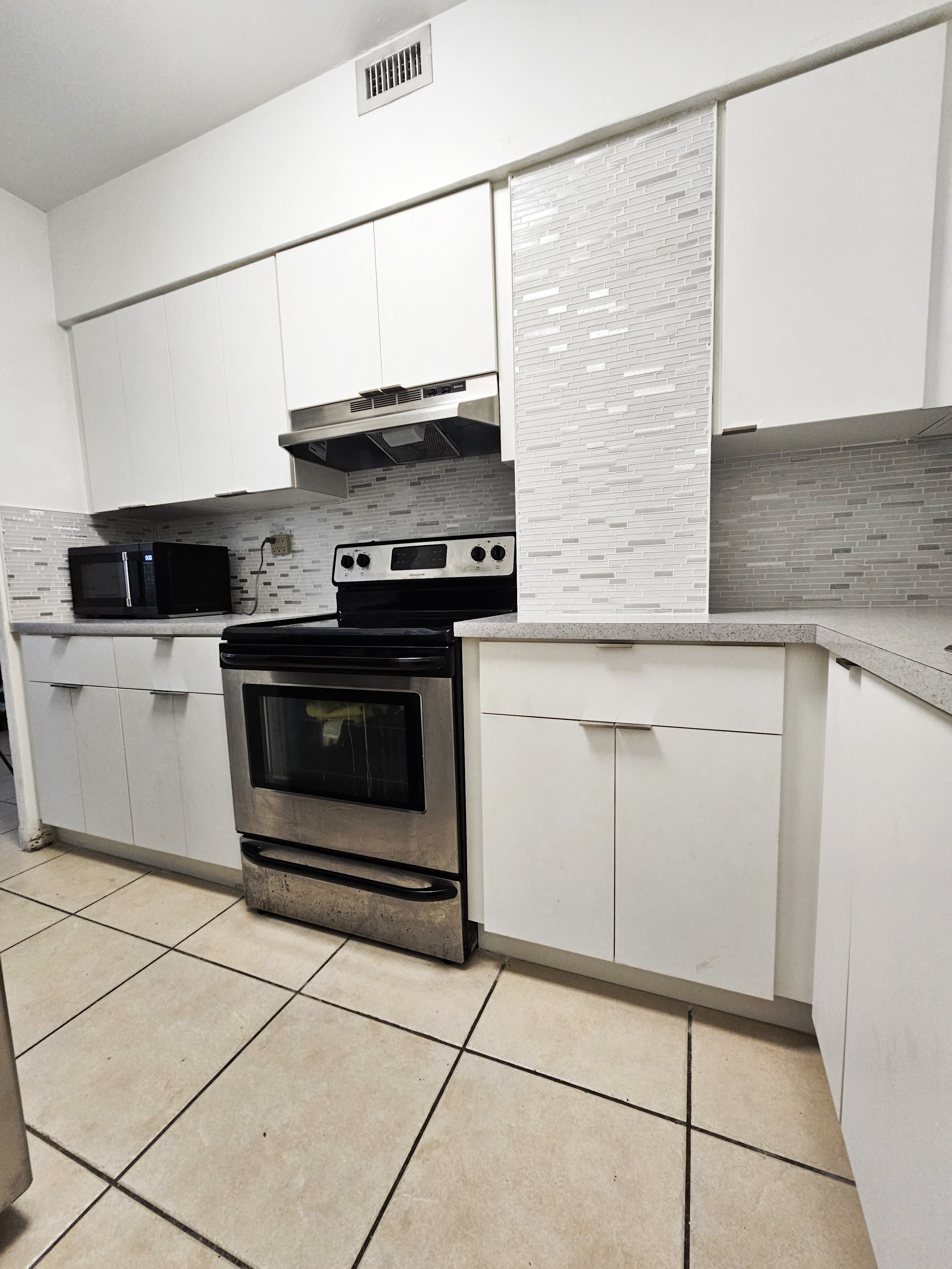 an empty kitchen with white cabinets and a stove and oven