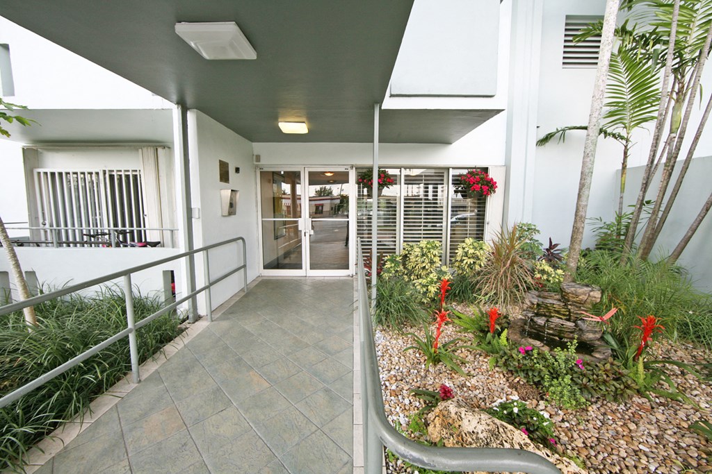 the entrance to a building with a garden on the side of it