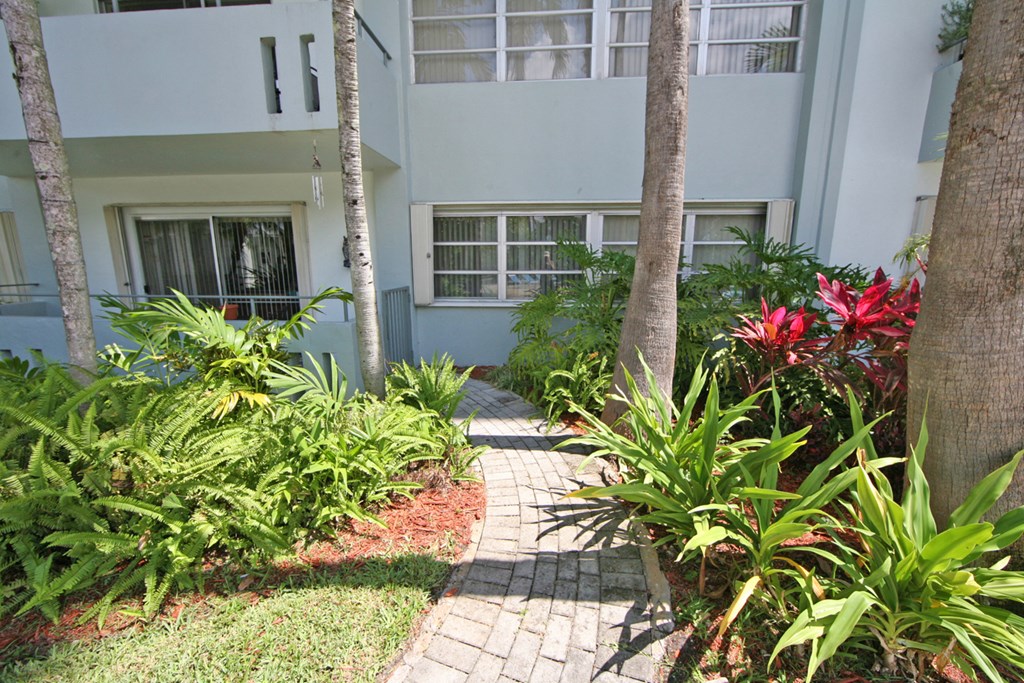 a pathway leading to a building with palm trees in front of it