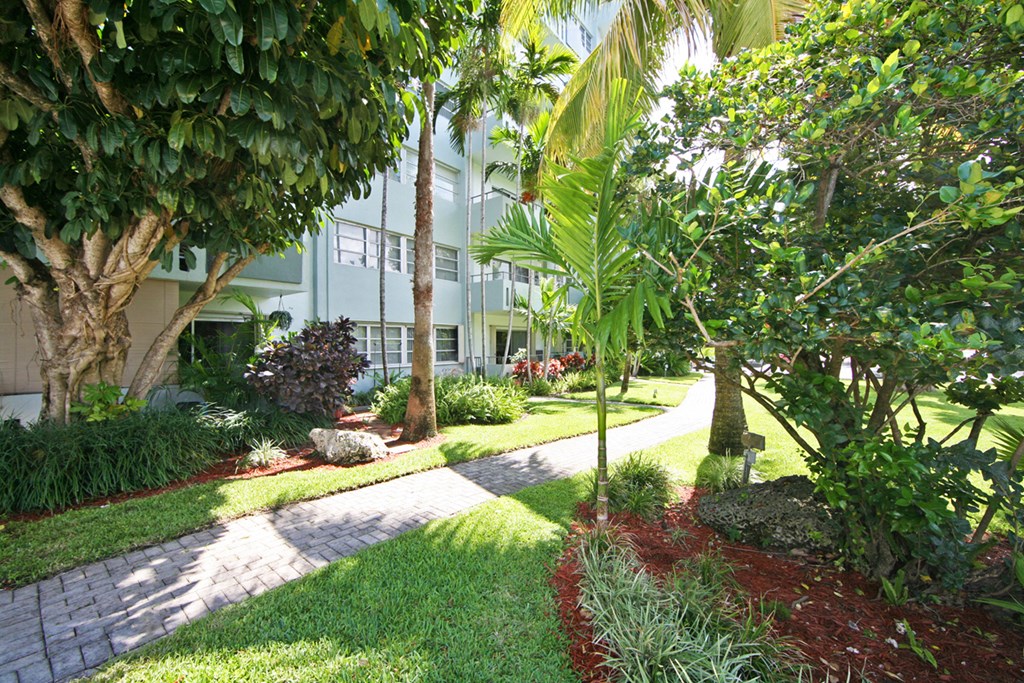 a walkway through a garden in front of a building