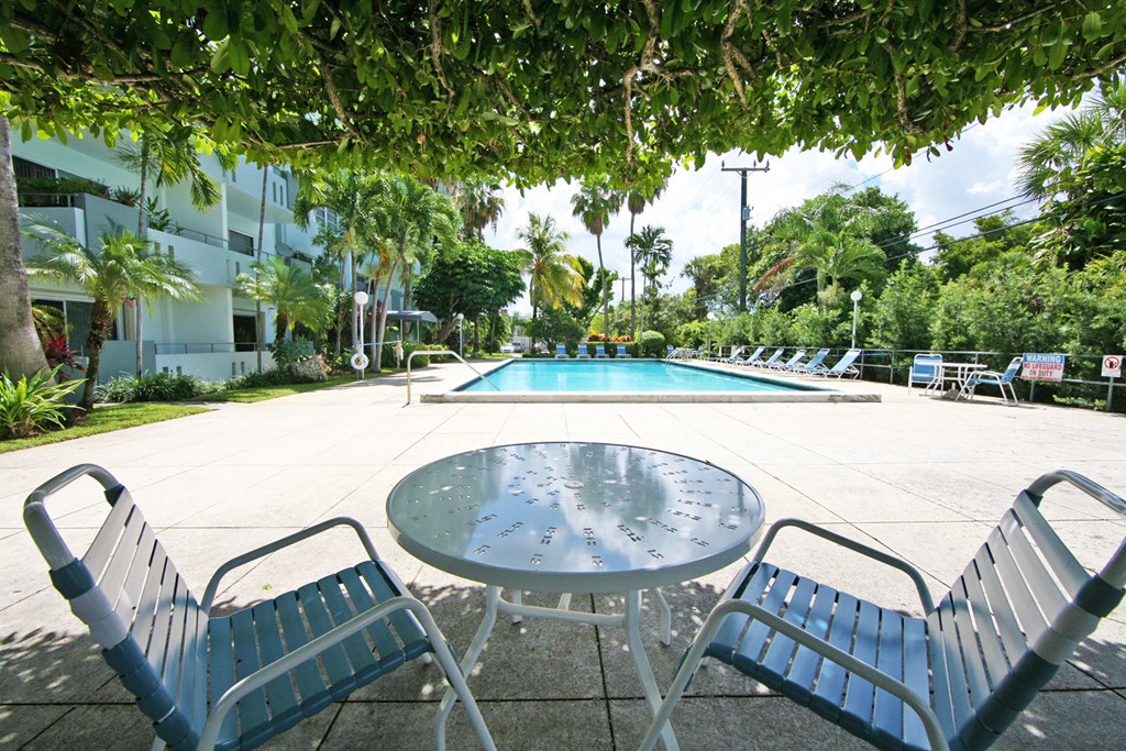 a patio with a table and chairs next to a swimming pool