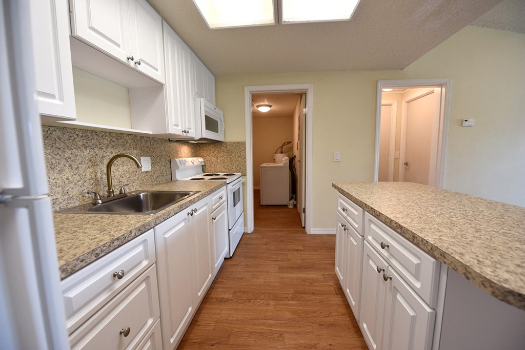 an empty kitchen with white cabinets and granite counter tops