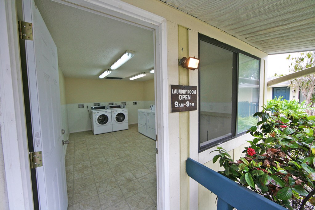 an open door leading into a laundry room with washing machines and a window