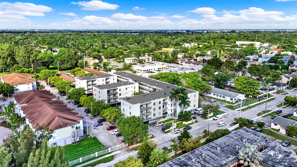 A large building with a red roof is surrounded by trees and other buildings.