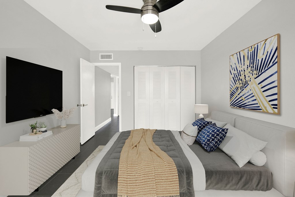 A bedroom with a bed, a ceiling fan, and a painting on the wall.