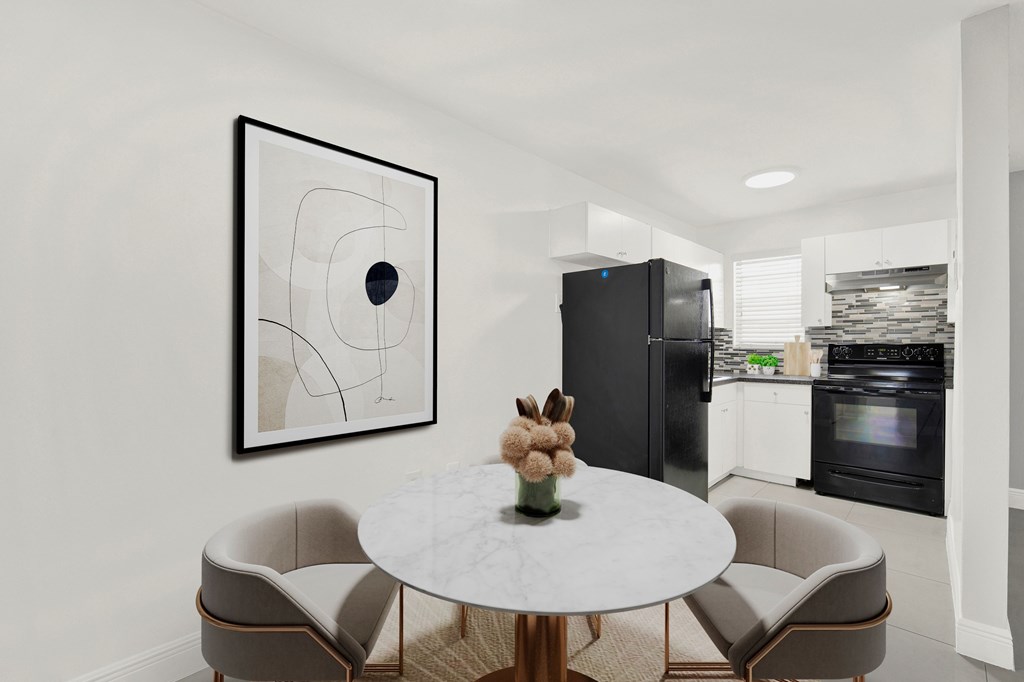 A modern kitchen with a round table and chairs, a fridge, and a painting on the wall.