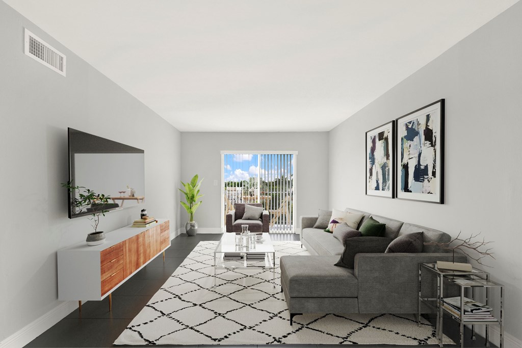 A living room with a grey couch, a black and white rug, and a television on the wall.