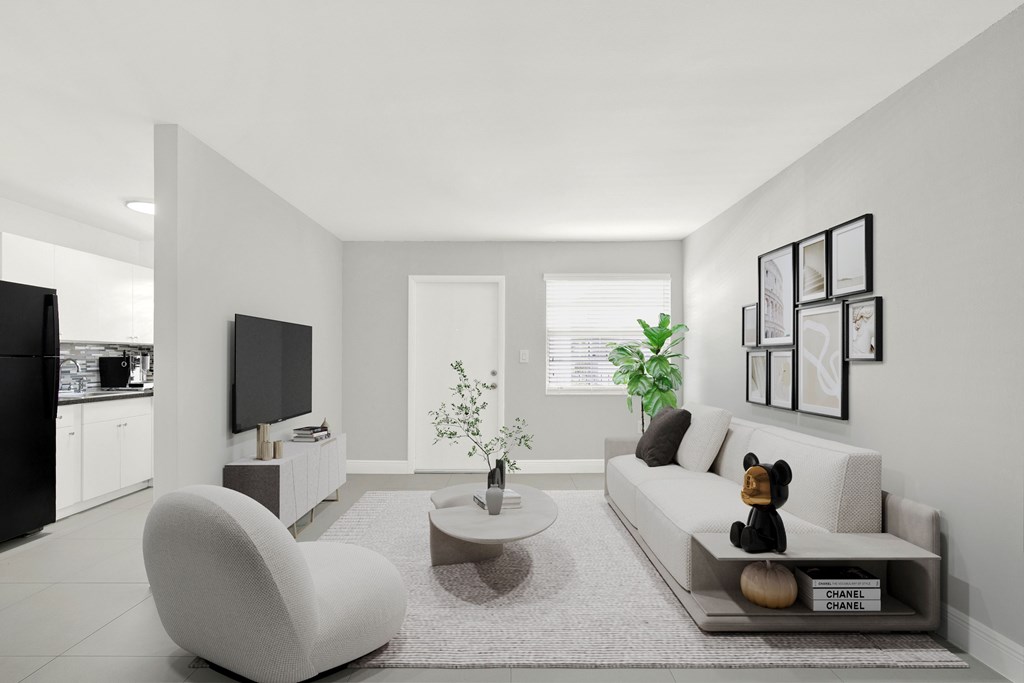 A modern living room with a white sofa, a grey armchair, a coffee table, and a TV.