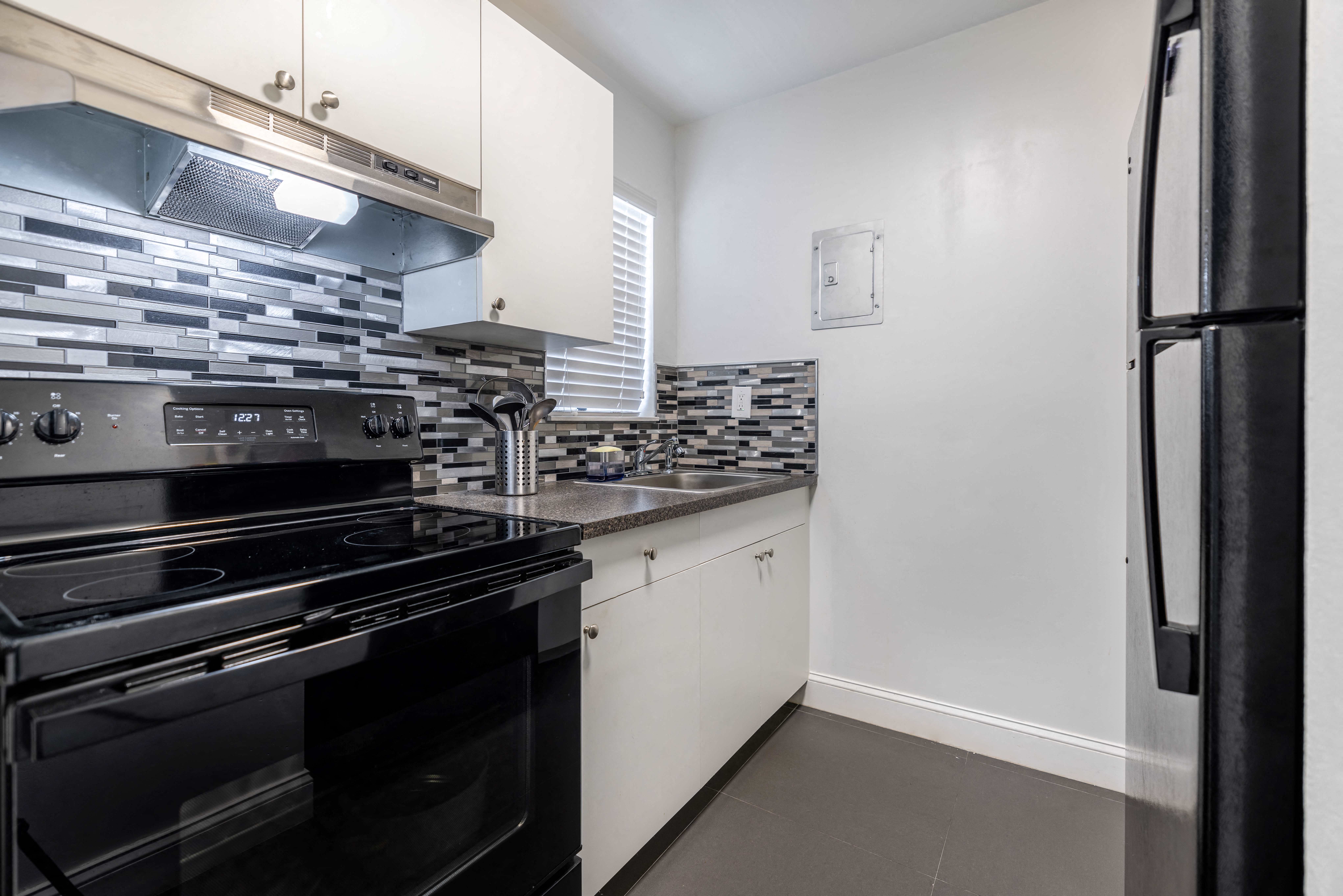 a renovated kitchen with black appliances and white cabinets