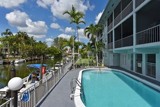 a large swimming pool in front of a building with palm trees
