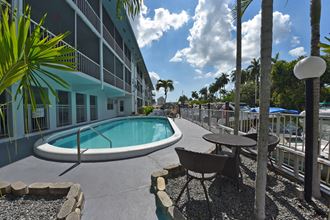 a swimming pool in front of a hotel with palm trees